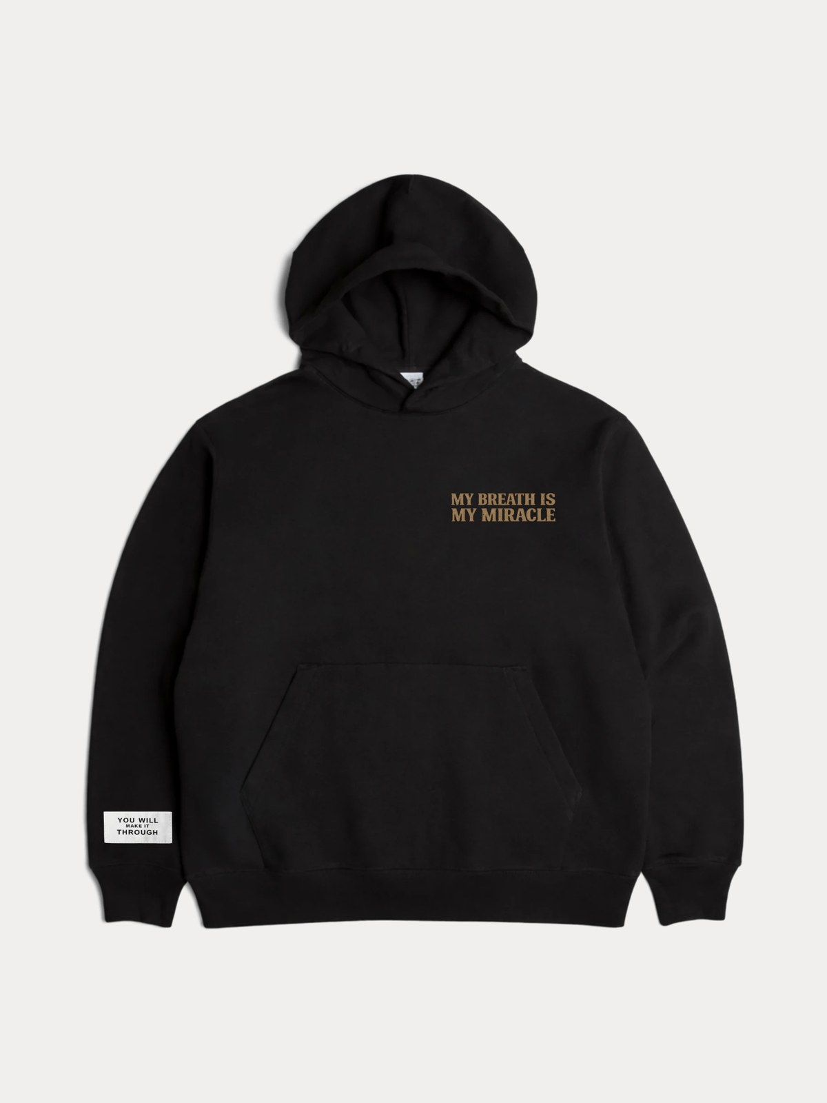 The My Breath Is My Miracle hoodie in black, the gold print on the left chest and the YOU WILL MAKE IT THROUGH sleeve label