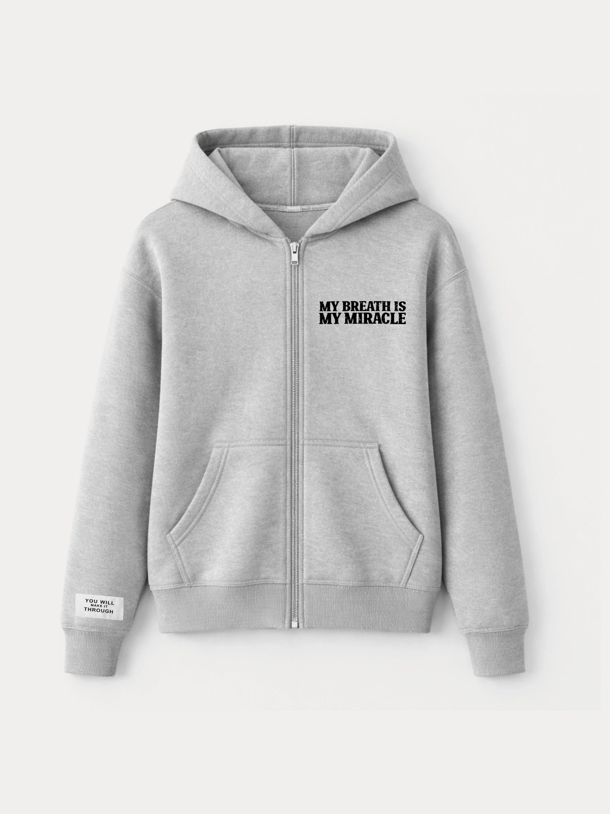 The My Breath Is My Miracle zip hoodie in heather grey, the black print on the left chest and the YOU WILL MAKE IT THROUGH sleeve label
